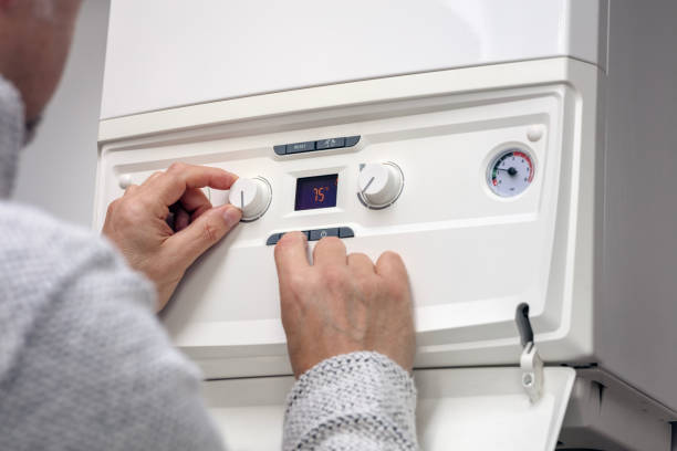 Technician adjusting a ducted heating control panel in a sunny Mornington living room